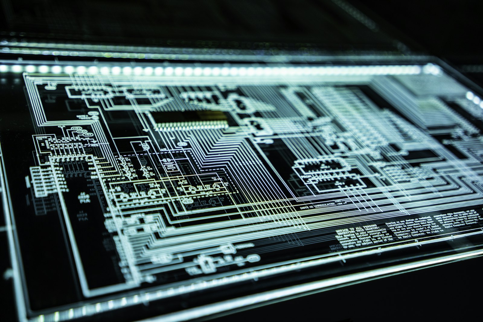 Illuminated circuit-board schematic glowing blue on dark glass